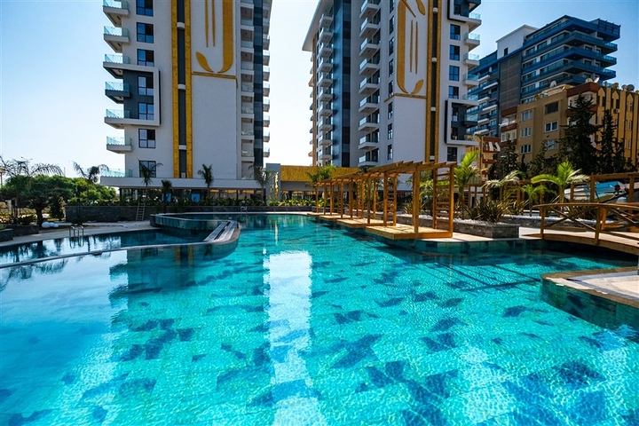 This functional one-bedroom apartment, with a total area of ​​57 sq m, is located on the second floor. The layout includes a bright living room with a kitchen area, a separate bedroom, a bathroom, and a balcony. The interior is fully furnished and equipped with appliances, air conditioning, ceramic tile flooring, a granite countertop in the kitchen, and a shower in the bathroom. This apartment is ideal for comfortable living in a vibrant coastal area. The project's infrastructure is designed for relaxation and an active lifestyle: an outdoor pool, an indoor pool, a children's pool, a water park, a sauna, a hammam, a steam room, a massage area, a fitness center, a tennis court, a volleyball court, a basketball court, table tennis, billiards, a children's play area, a green garden, a barbecue area, walking paths, a games room, internet access, television, a café, a pool bar, a conference room, a generator, outdoor parking, indoor parking, security, and a video surveillance system. Sea View Apartment with Furniture on Cebeci Towers Alanya Turkey